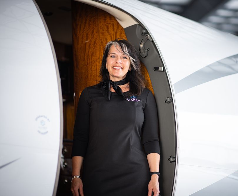 Aircraft hostess standing in doorway of private jet