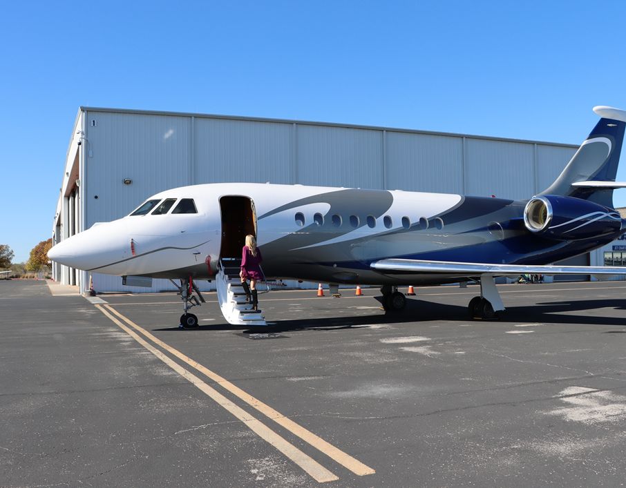 Woman walking up steps to a private jet on the runway