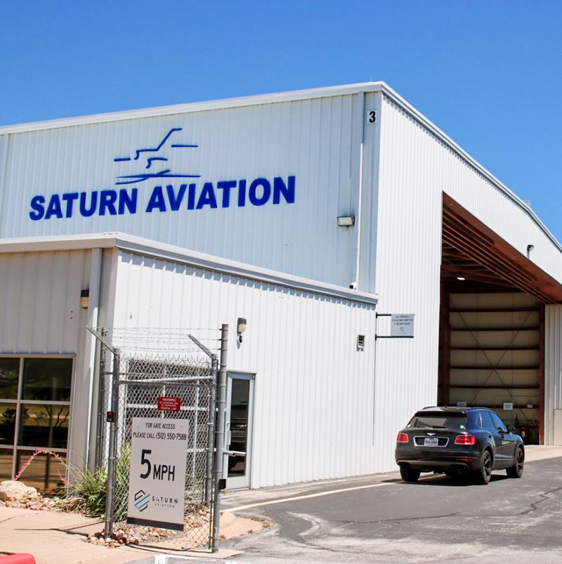 White hangar with Saturn Aviation written in blue letters on the side
