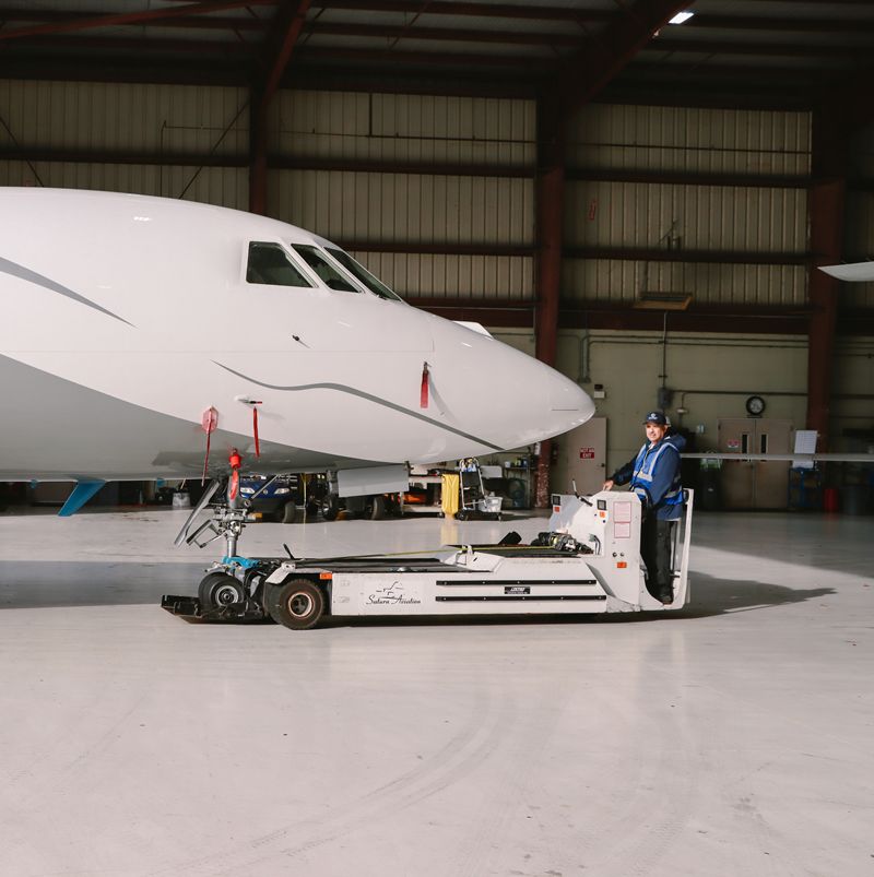 Front of a private jet in a hangar with a maintenance tech